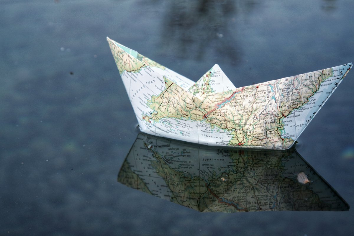 Paper boat folded from a world map, floating on water